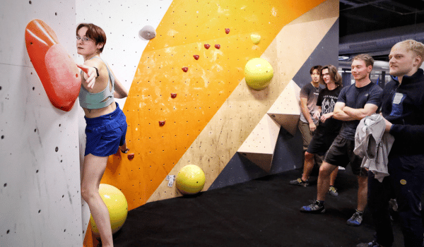 female climbs wall as friends watch - boardroom climbing wimbledon