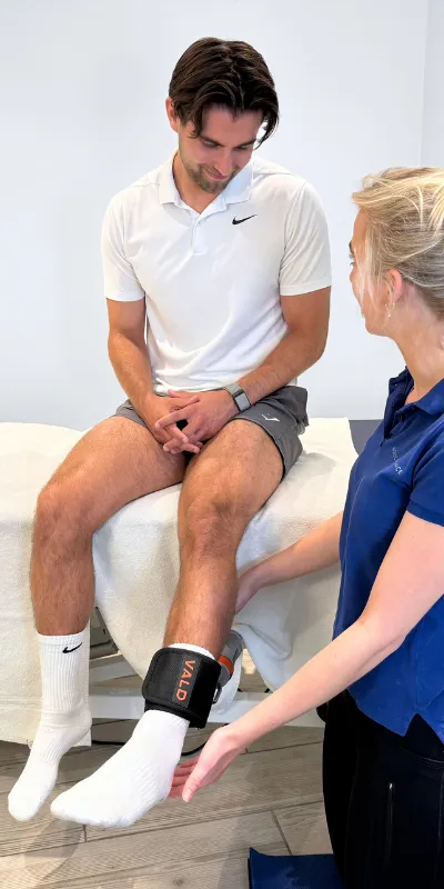 Nordic Balance physiotherapist measuring lower-leg strength with a VALD DynaMo device.