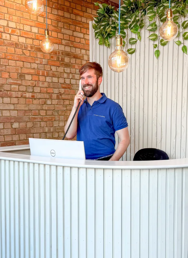 Nordic Balance team member speaking with a client by phone at the clinic reception desk.