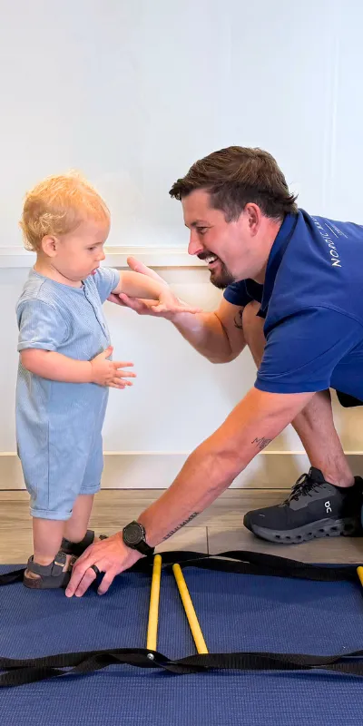 Nordic Balance physiotherapist supporting a toddler through a movement exercise using agility equipment.
