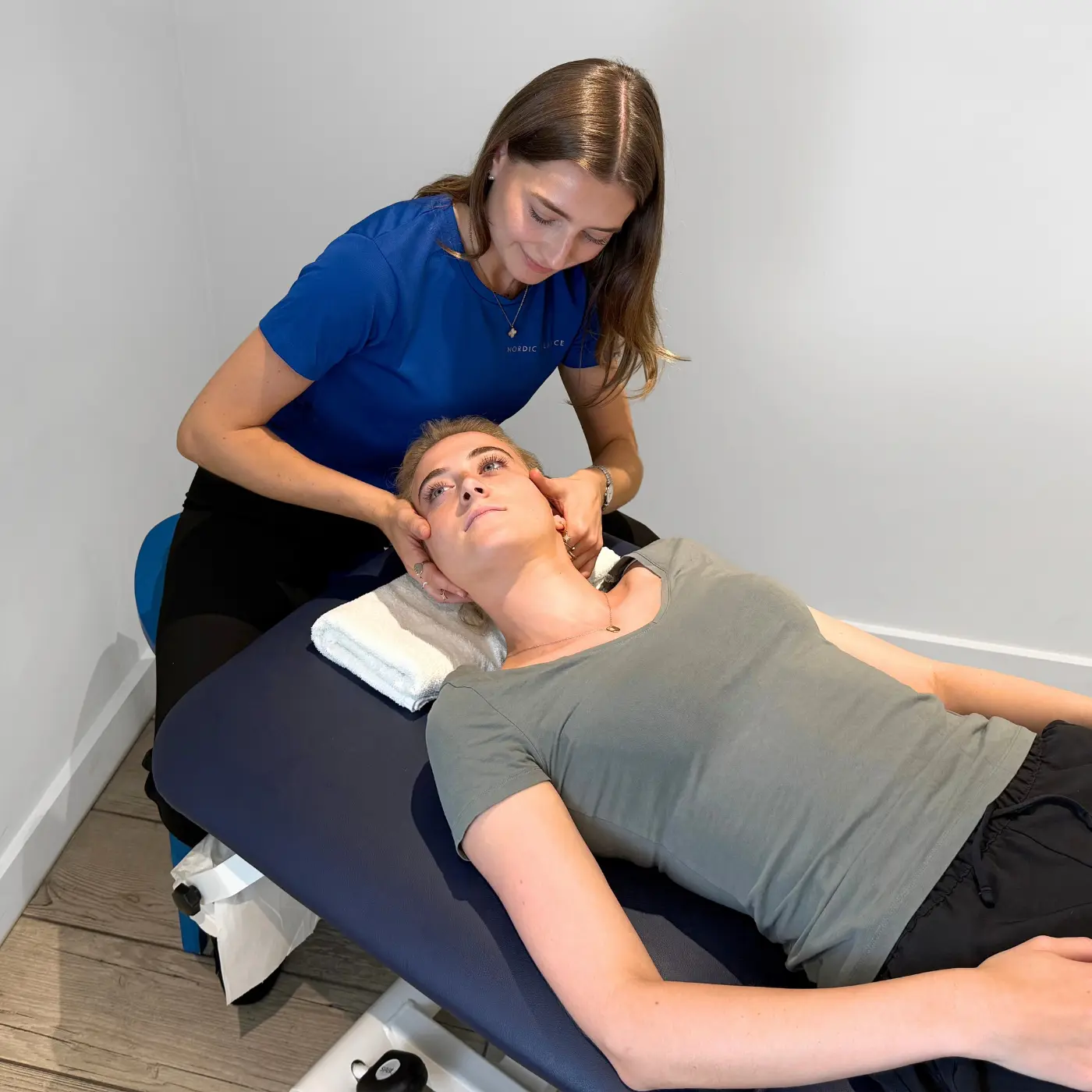 Osteopath at Nordic Balance assessing a woman’s neck mobility and alignment while she lies on a treatment table.