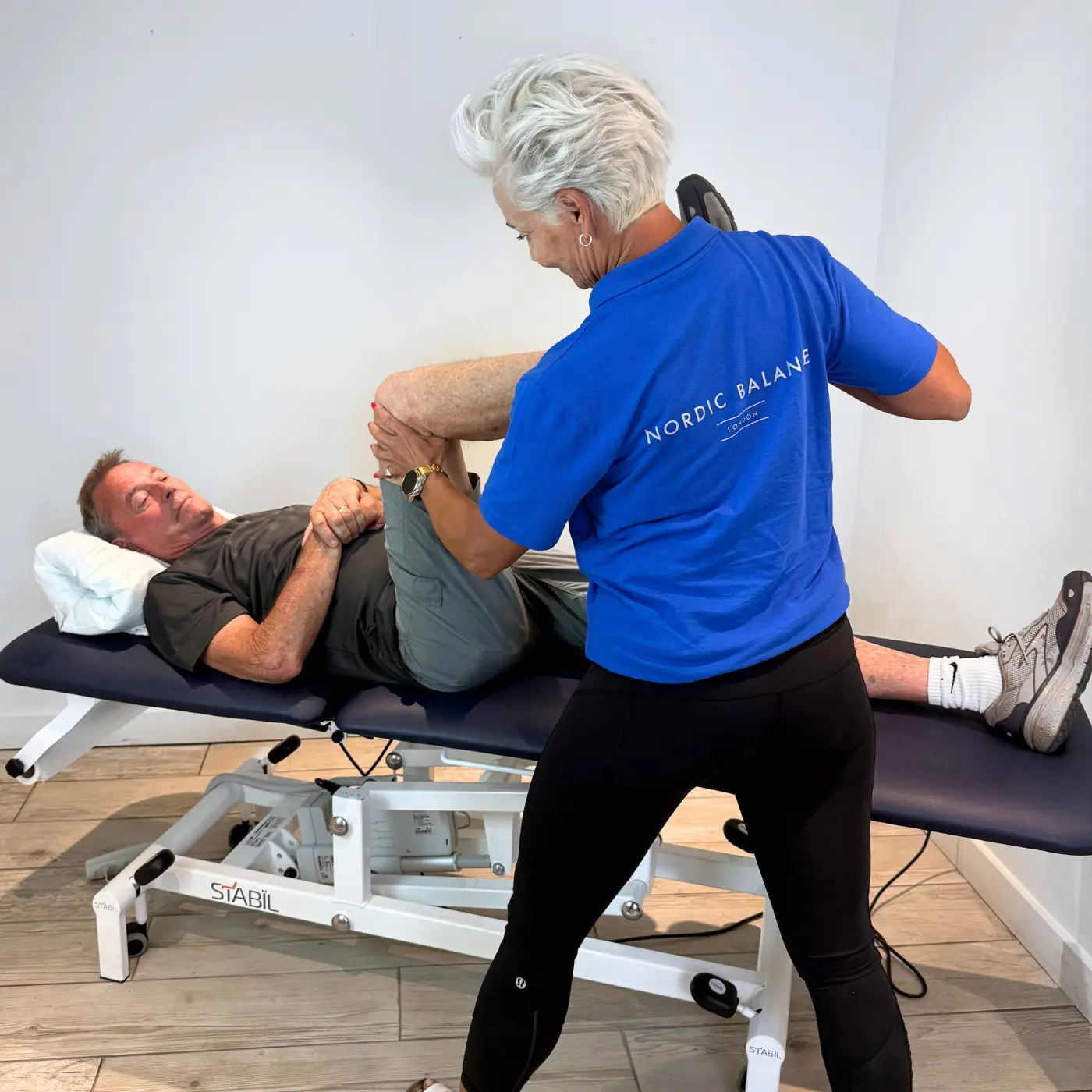 Chiropractor at Nordic Balance assessing a patient’s hip mobility and leg movement on a treatment table.