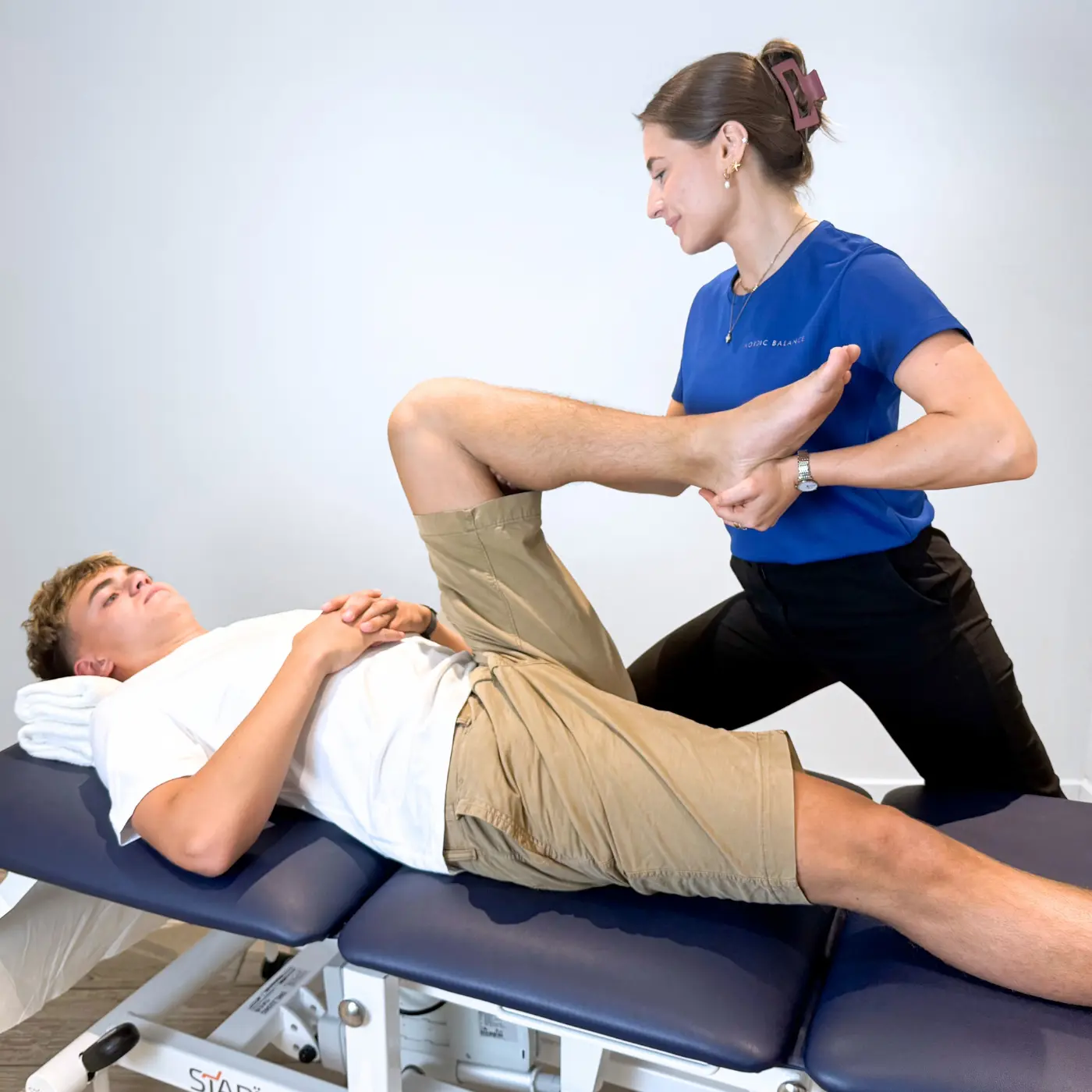 Paediatric osteopath at Nordic Balance assessing a teenager’s hip mobility and range of motion on a treatment table.