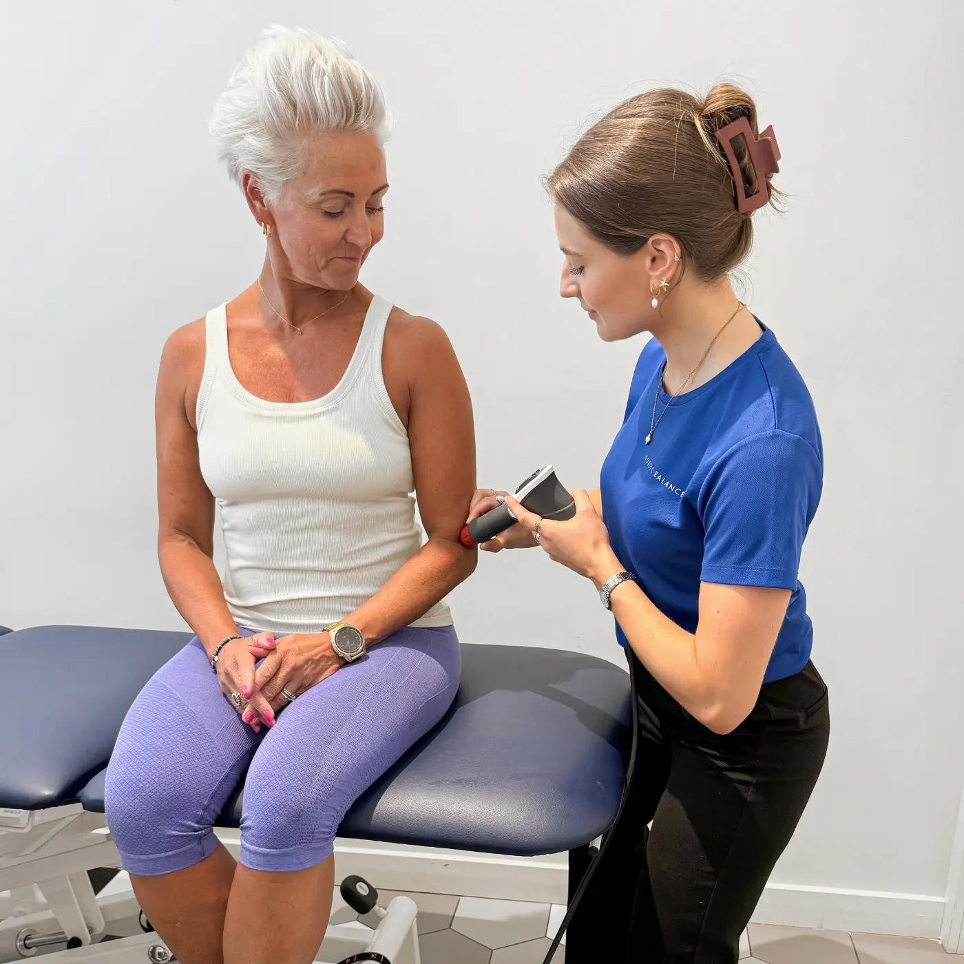 Shockwave therapy at Nordic Balance, with a therapist applying a handheld shockwave device to a woman’s elbow.
